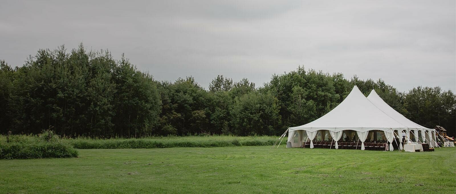 Tent Rentals Calgary featuring a white Pole Pent on a grassy field for a wedding reception.